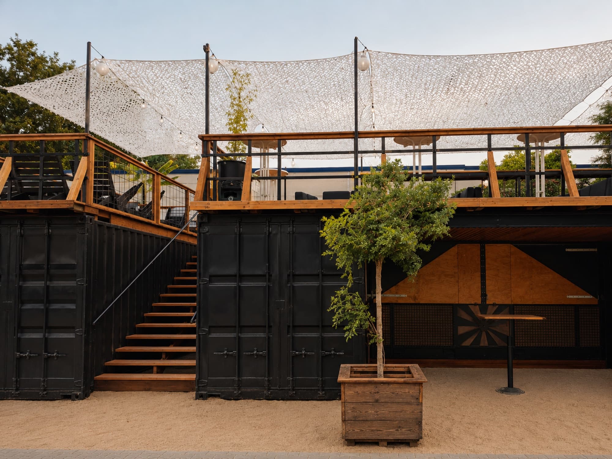The steps up to the press area deck at Berliner Berg Brauerei, above the black shipping containers on the sand.